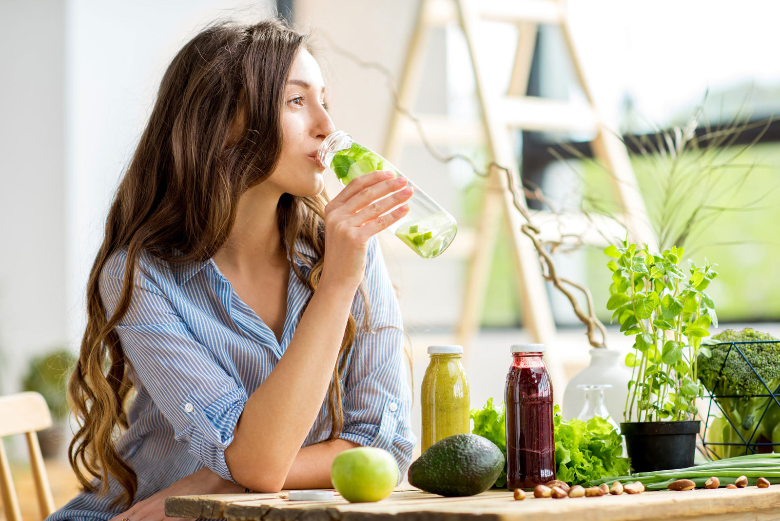 a young woman drinking a healthy drink sitting at a table