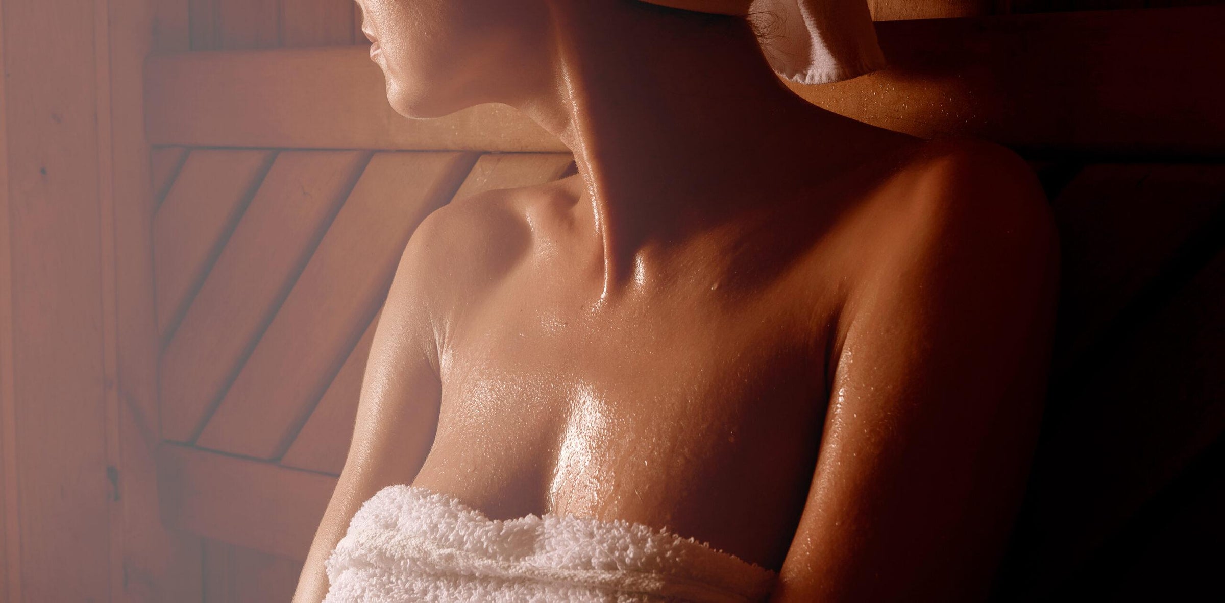 a woman sitting in a sauna sweating with a towel around her