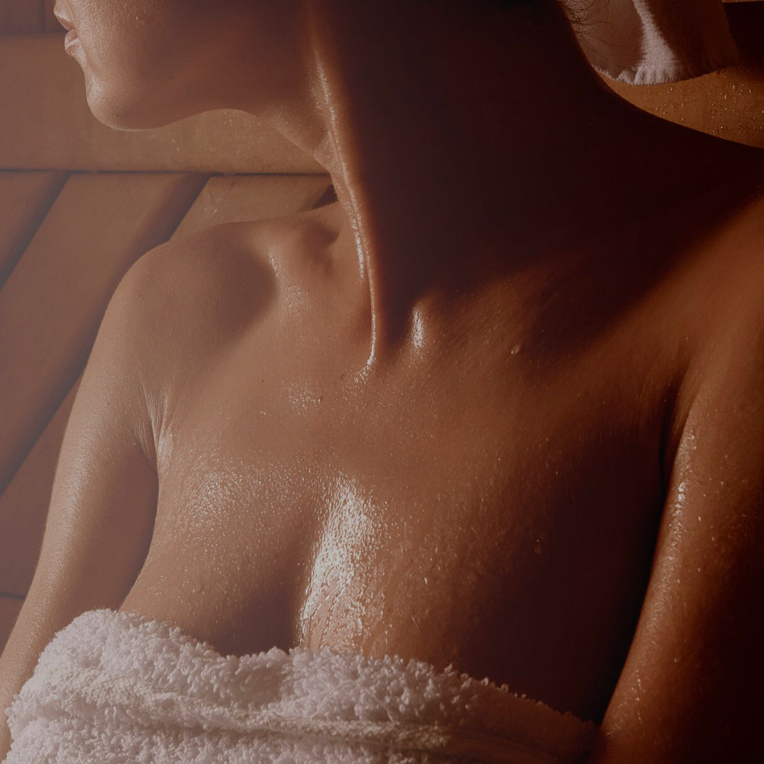 a photo of a woman sitting in a sauna with a towel